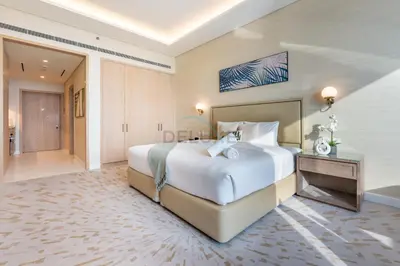 a bedroom with a large white bed and a bathroom at Steps from Nakheel Mall and Monorail Station, Near Beach Clubs ,15 Mins to Downtown and Marina, The Palm Tower, Palm Jumeirah by Deluxe Holiday Homes in Dubai