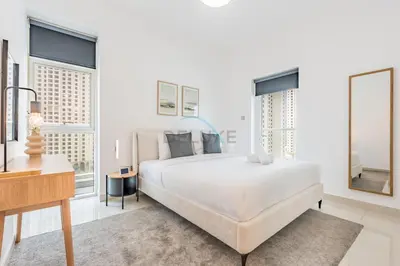 a white bedroom with a large bed and windows at Seamless Access to Marina Mall, JBR Beach, Dining And Shopping Spots, Just A Few Meters from the Tram Station - Continental Tower, Dubai Marina by Deluxe Holiday Homes in Dubai