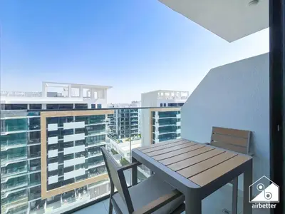 a balcony with a wooden table and chairs on a balcony at Amazing Studio in Meydan l Pool , Gym & Balcony in Dubai