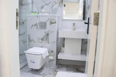 a white bathroom with a toilet and a sink at Dubai Marina 1BR with Balcony, Near Metro, Walk to JBR beach & Marina Promenade in Dubai