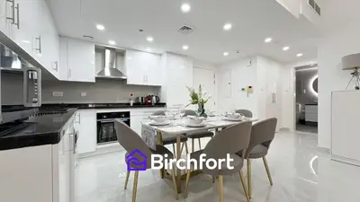 a white kitchen with a dining table and chairs at Birchfort- Downtown Living with Burj Khalifa View in Dubai