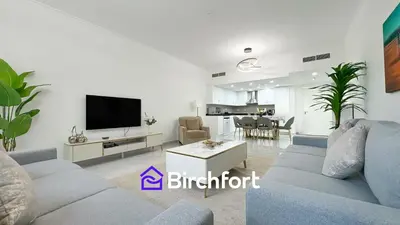 a living room with a blue couch and a kitchen at Birchfort- Downtown Living with Burj Khalifa View in Dubai