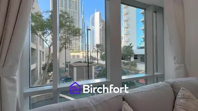 a living room with a couch and a large window at Birchfort- Downtown Living with Burj Khalifa View in Dubai