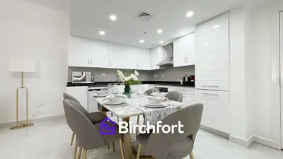 a white kitchen with a dining table and chairs at Birchfort- Downtown Living with Burj Khalifa View in Dubai