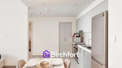 a white kitchen with a table and chairs at Elegant Flat in Prime Location in Dubai