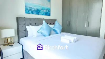 a bedroom with a bed with blue and white pillows at Elegant Flat in Prime Location in Dubai