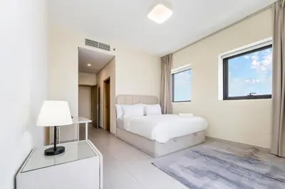 a white bedroom with a bed and a window at FAM Living - 2BR Apartment with Burj & Canal Views at The Bay in Dubai