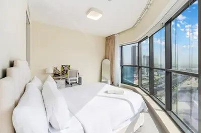 a bedroom with a white bed and a large window at FAM Living - 2BR Apartment with Burj & Canal Views at The Bay in Dubai