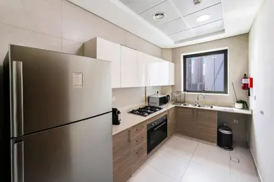 a kitchen with a stainless steel refrigerator and a sink at FAM Living - 2BR Apartment with Burj & Canal Views at The Bay in Dubai
