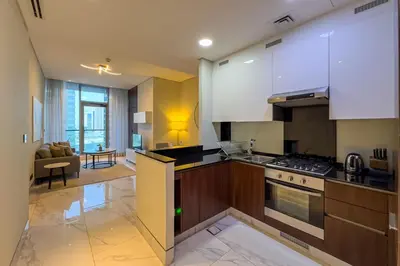 a kitchen with white cabinets and a living room at Stylish 1B in J one With Balcony & Canal View in Dubai