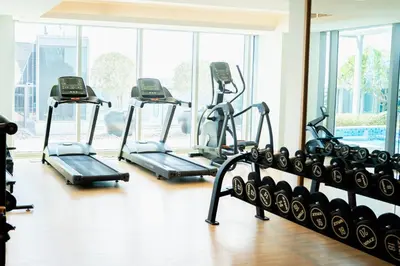a gym with several tread machines in a room at 1BR City Escape l Canal & Skyline Views in Dubai