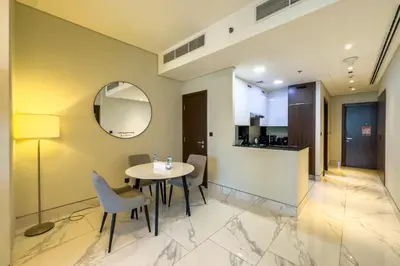 a dining room with a table and chairs and a mirror at 1BR City Escape l Canal & Skyline Views in Dubai