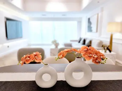 three white vases with flowers on a table in a living room at SOLARTE Luxe - New Large 2BR - Marina Promenade - Sea Views - Super King Bed & Workspace in Dubai