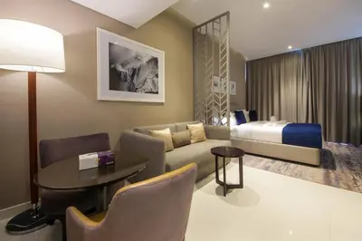 a living room with a bed and a couch and a table at Cozy Studio in Damac Prive - Free Gym & Pool in Dubai