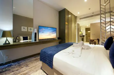 a hotel room with a bed and a flat screen tv at Cozy Studio in Damac Prive - Free Gym & Pool in Dubai
