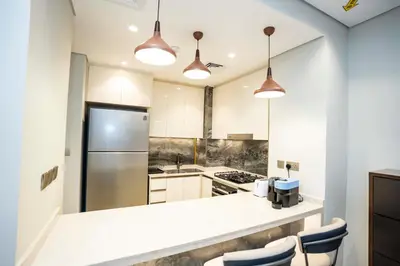a kitchen with white cabinets and a stainless steel refrigerator at Spacious Luxe 2BR in Dubai - With Pool and Gym in Dubai