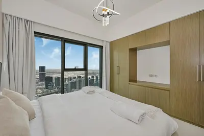 a bedroom with a white bed and a large window at Golden Stays - Sky High 2BR I Burj Khalifa Views & Mallside Charm I Dowtown Dubai in Dubai