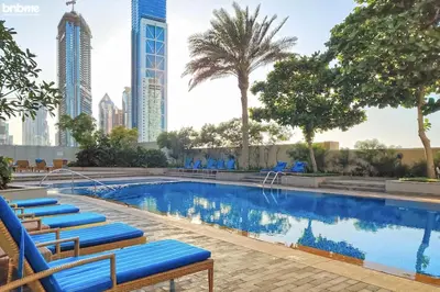 a swimming pool with blue lounge chairs and tall buildings at bnbmehomes - The Lofts Central in Dubai