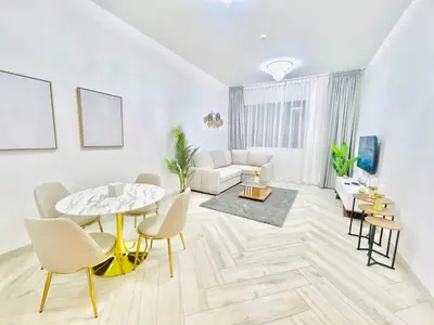 a living room with a table and chairs and a couch at Stylish 1 Bedroom Apartment in the Heart of JVC in Dubai