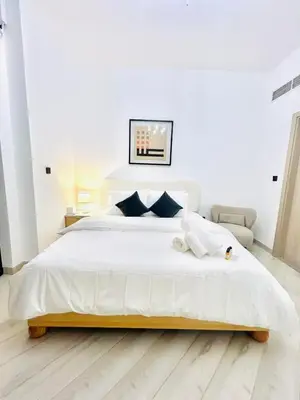 a white bedroom with a large white bed with blue pillows at Stylish 1 Bedroom Apartment in the Heart of JVC in Dubai