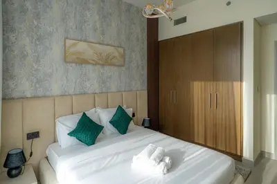 a bedroom with a large white bed with green pillows at Elegant Downtown Escape 1BR w Balcony, Pool & Gym in Dubai