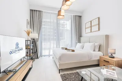 a white bedroom with a bed and a tv at Bright Modern Studio in the Heart of JVC in Dubai