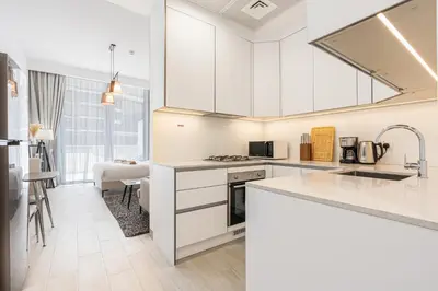 a kitchen with white cabinets and a counter top at Bright Modern Studio in the Heart of JVC in Dubai