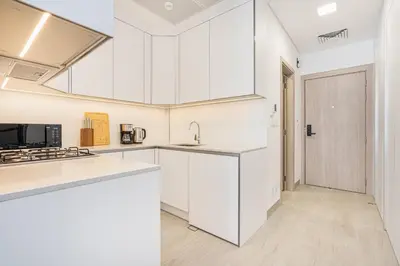 a kitchen with white cabinets and a sink at Bright Modern Studio in the Heart of JVC in Dubai