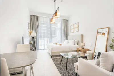 a white living room with a bed and a table at Bright Modern Studio in the Heart of JVC in Dubai