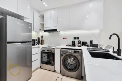 a white kitchen with a washing machine and a dishwasher at Bookable - 1 Bedroom Binghatti Crescent in Dubai