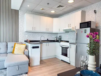 a kitchen with white cabinets and a couch in a room at Luxury Studio Apartment with large Balcony and Sea Views, free Parking, Dubai Marina - JBR in Dubai