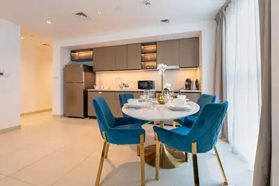 a dining room with a table and blue chairs at Boulevard Views, Steps from Burj Khalifa & Dubai Mall, Near Metro Station and Few Mins Drive to Dubai Marina - Burj Crown, Downtown Dubai by Deluxe Holiday Homes in Dubai