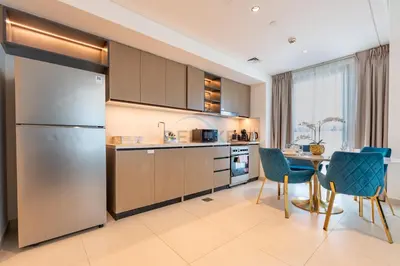 a kitchen with stainless steel appliances and a table and chairs at Boulevard Views, Steps from Burj Khalifa & Dubai Mall, Near Metro Station and Few Mins Drive to Dubai Marina - Burj Crown, Downtown Dubai by Deluxe Holiday Homes in Dubai