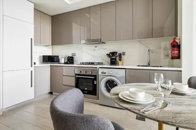 a kitchen with a table and chairs and a kitchen with a dishwasher at 1BR Azizi Riviera 44 City Skyline View in Dubai