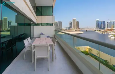 a balcony with a table and chairs on a building at Blue Breeze - Stunning 1BR with Canal & Pool Views in Dubai