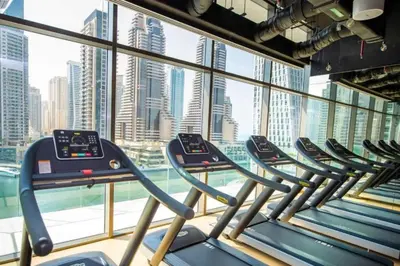 a row of treadmills in a gym with a city view at Marina Gate 2 - High Rise One Bed with Marina View in Dubai