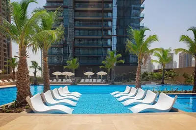 a swimming pool with white chairs and palm trees at Marina Gate 2 - High Rise One Bed with Marina View in Dubai