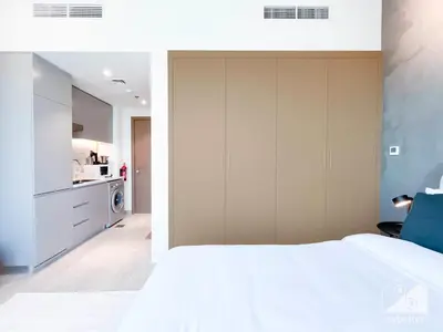 a bedroom with a white bed and a kitchen at Breathtaking Studio with Balcony & Stunning Views in Dubai