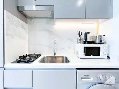 a white kitchen with a sink and a microwave at Breathtaking Studio with Balcony & Stunning Views in Dubai