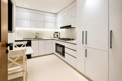 a white kitchen with white cabinets and appliances at 2BR Luxury Baby, Gym & Pool in Dubai