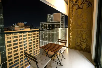 a balcony with two chairs and a wooden table on a building at 2BR Luxury Baby, Gym & Pool in Dubai