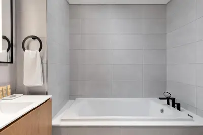 a white bathroom with a tub and a sink at Maison Privee - Sky-High Panoramic Apt with Iconic Burj Khalifa Vws in Dubai
