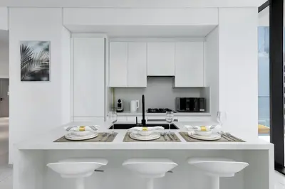 a white kitchen with white cabinets and white dishes on a counter at Maison Privee - Sky-High Panoramic Apt with Iconic Burj Khalifa Vws in Dubai