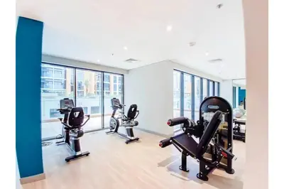 a gym with three treadmills and elliptical machines at Guest Favorite - Relaxed and Cozy Studio Near Racecourse in Dubai