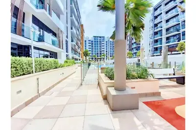 a walkway in a city with palm trees and buildings at Guest Favorite - Relaxed and Cozy Studio Near Racecourse in Dubai