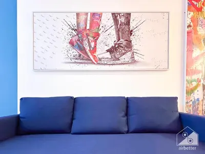 a painting on the wall above a blue couch at Colorful Studio with Balcony & City Views in Dubai