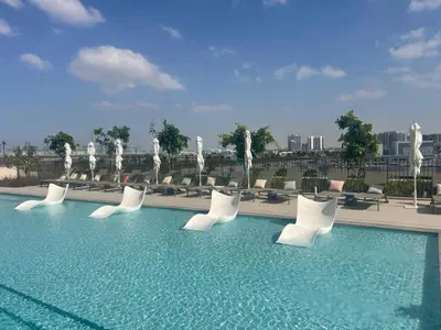 a swimming pool with white chairs and a fountain at Walk to Dubai Hills Mall, Premium Amenities And Near Dubai Hills Park And Golf Club, Socio Tower 1, Dubai Hills by Deluxe Holiday Homes in Dubai