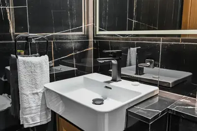 a white sink in a bathroom with black tiles at Golden Stays - Private Pool in Binghatti Onyx I Modern 2BR Apartment I JVC Dubai in Dubai