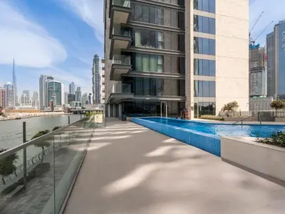 a building with a swimming pool next to a river at Stunning 1BR Canal Front Residence near Downtown in Dubai