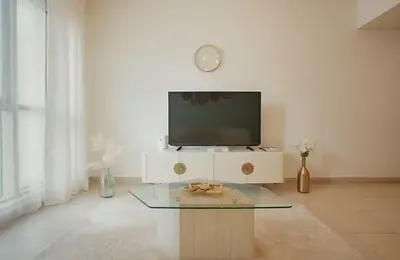 a living room with a tv and a glass table at Burj View 1BR Pool,Gym,Sauna,Dubai Mall in Dubai